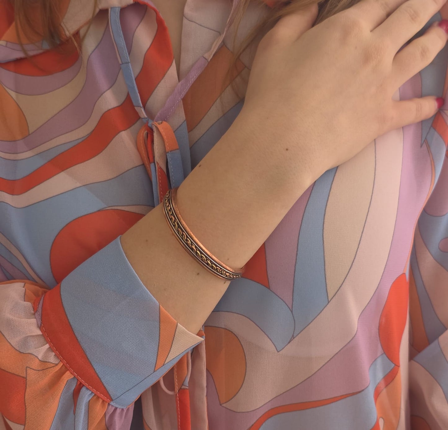Bracciale in rame con dettagli intrecciati color oro indossato